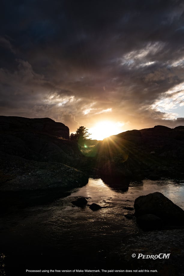 the sun is setting over a rocky shore with rocks and water