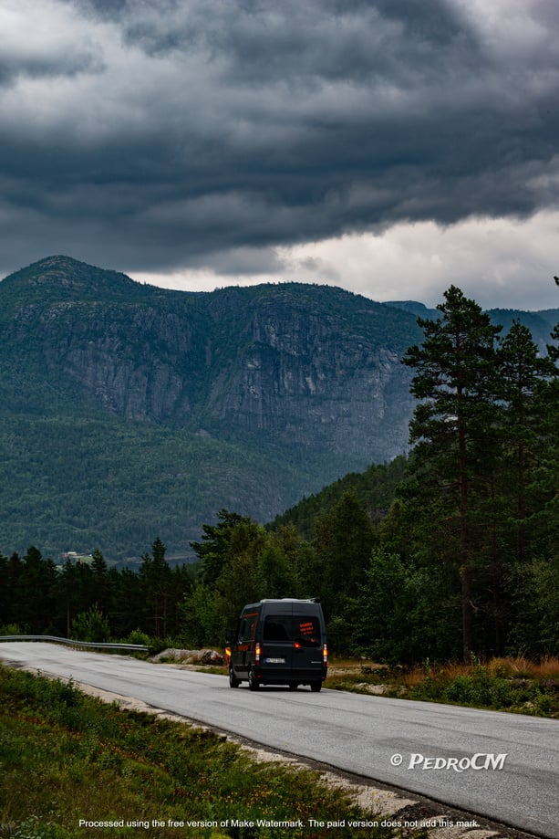 a van driving down a road with mountains in the background